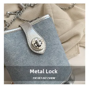 Close-up of the silver hardware lock and metal chain on a light blue textured bucket bag