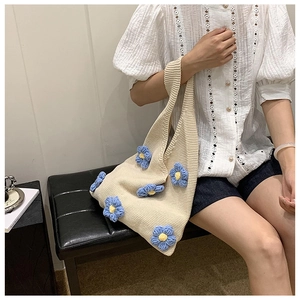 Détail du sac cabas en crochet fait main avec des fleurs en tricot 3D bleues et jaunes