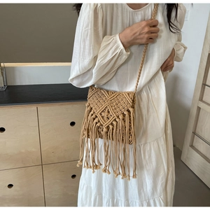 Detail of bohemian woven straw bag featuring intricate diamond patterns and long tassels