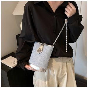 Close-up of silver-tone chain strap and bucket bag detail with metallic leather trim