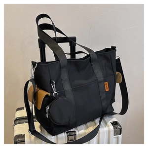 Detail of black nylon tote bag with round coin purse on a silver suitcase