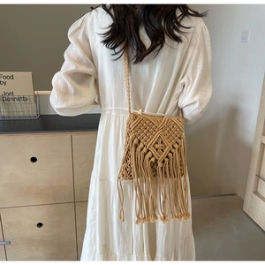 Detail of bohemian woven straw bag showing long tassels and intricate crochet texture