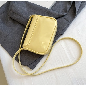 Top-down view of a small pale yellow PU leather crossbody bag on a grey blazer fabric