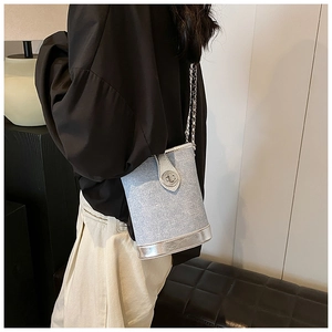 Detail of silver chain strap on light blue metallic bucket bag worn by model
