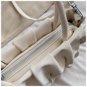 Macro view of creamy white pleated handbag showing metal zipper and silver hardware details