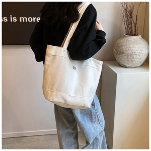 Detailed texture of a minimalist cream canvas tote bag with a small metal buckle detail
