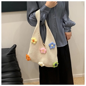 Détail de fleurs au crochet colorées sur la texture d'un sac cabas en maille crème