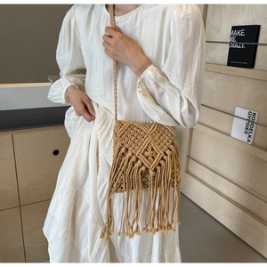 Detail of bohemian beige woven crossbody bag featuring intricate crochet and long tassels