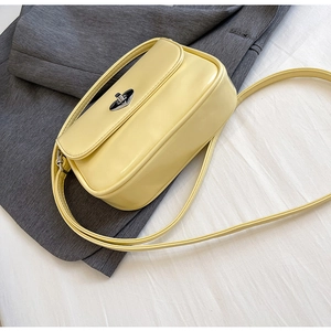 Detail of light yellow leather crossbody bag featuring a polished silver twist lock closure
