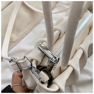 Detailed close-up of cream pleated cloud bag with silver zipper and metal lobster clasp