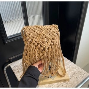 Close-up of Bohemian straw woven bag with long fringe and diamond knit patterns