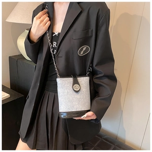 Detailed view of the crossbody bucket bag with grey fabric, leather base and silver chain