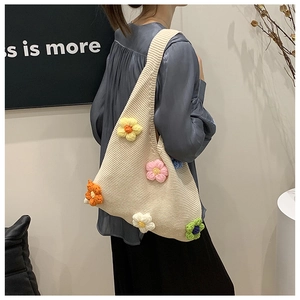 Détail d'un sac cabas en tricot beige avec des fleurs 3D au crochet sur un mannequin
