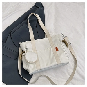 Detail of white nylon tote bag with round coin purse charm and orange brand label