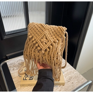 Detail of bohemian straw bag featuring handmade cotton rope weave and long fringe tassels