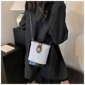 Detail of denim bucket bag with black leather trim and silver metal twist lock closure
