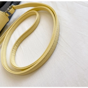 Close-up of yellow PU leather bag strap with silver metal buckle and neat stitching