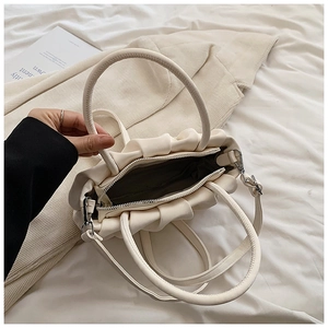 Detail view of white ruched handbag interior with dark lining and zipper pocket