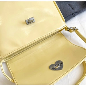 Detailed close-up of a yellow PU leather bag featuring a silver heart-shaped twist lock