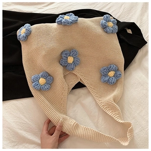 Détail du sac en maille beige avec fleurs bleues en crochet 3D sur tissu doux