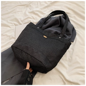 Detail of large black denim tote bag with golden metal logo and spacious interior view