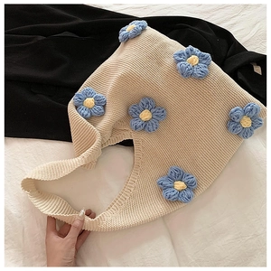 Gros plan du sac fourre-tout en maille crème avec fleurs crochetées en bleu et jaune