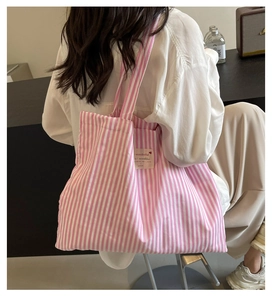 Woman carrying a pink and white striped canvas tote bag in a cozy lifestyle setting