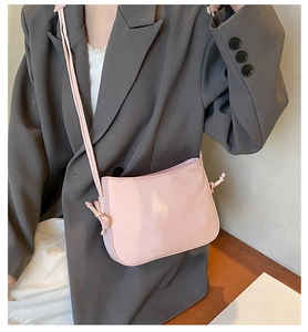 Détail du sac bandoulière rose clair avec nœuds décoratifs et finition satinée lisse