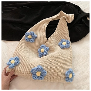Détail d'un sac cabas tricoté à la main avec fleurs 3D bleues sur fil crème