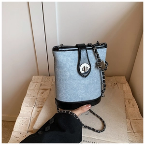 Detail of light blue denim bucket bag with black leather trim and silver twist lock