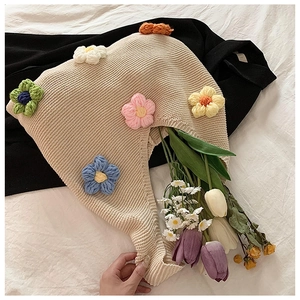 Détail d'un sac en maille beige avec fleurs au crochet 3D et tulipes fraîches