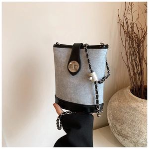 Detail of blue denim bucket bag featuring black leather trim and silver metal twist lock