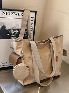 Large beige nylon tote bag with adjustable strap and mini coin purse in a modern setting