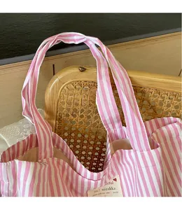 Detail of pink and white striped canvas tote bag showing wide straps and fabric label