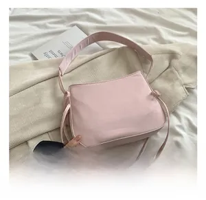 Détail du sac à bandoulière rose en toile avec nœud décoratif et texture tissu doux