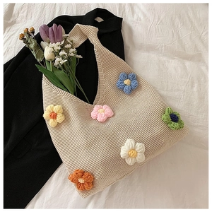 Détails de fleurs crochetées colorées sur une texture de sac cabas en tricot beige