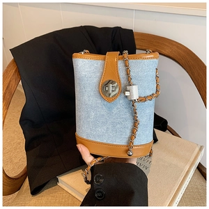 Detail of blue denim bucket bag with brown leather trim and silver twist lock