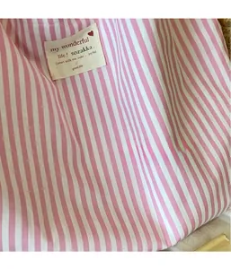 Close-up of pink and white striped canvas tote material with a stitched brand label