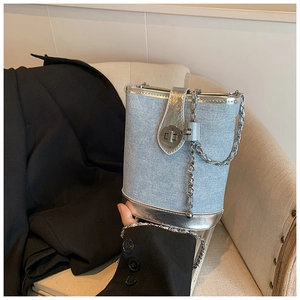 Detail of light blue denim bucket bag with silver leather trim and metal chain strap