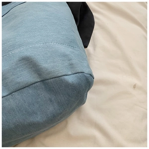 Detail of light blue denim fabric texture and reinforced stitching on a large tote bag
