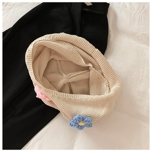 Gros plan du sac en tricot beige montrant les motifs floraux et la texture de laine épaisse