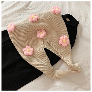 Détail du sac cabas au crochet avec fleurs roses sur une surface en maille beige