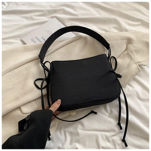 Détail du sac à bandoulière en toile noire avec cordons latéraux et large bandoulière