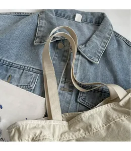 Detailansicht des breiten Webriemens einer beigen Segeltuch-Tasche im Freizeitlook