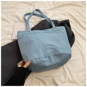 Close-up of light blue denim tote bag with visible stitching and soft textile texture