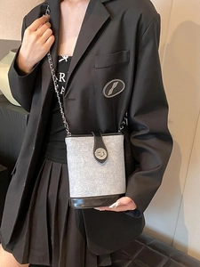 Fashionable grey patchwork crossbody bucket bag with metal chain strap on female model