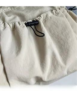 Detail der hellbeigen Tasche aus gewaschenem Stoff mit verstellbaren Kordelzügen und Kordelstoppern