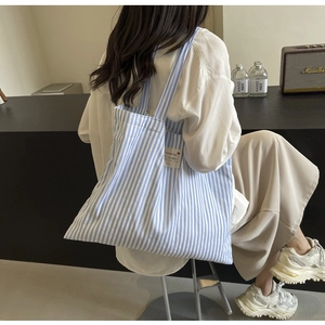 Detailed view of a blue and white striped canvas tote bag with functional side pocket