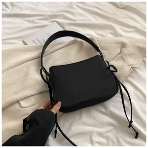 Gros plan sur la texture tissée noire et les détails du cordon réglable du sac à bandoulière