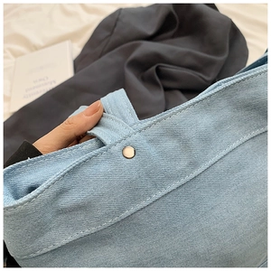 Macro view of light blue denim tote showing silver rivet details and sturdy stitching